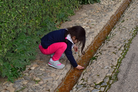 child playing with water in alhambra irrigation ditch