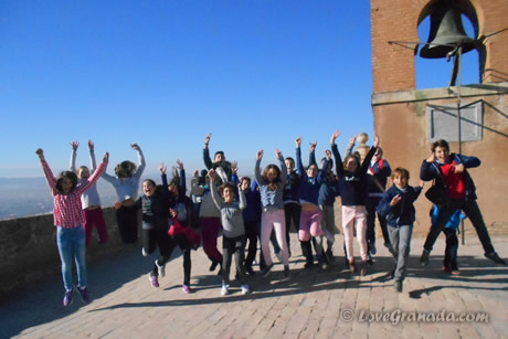 children jumping next to bell tower