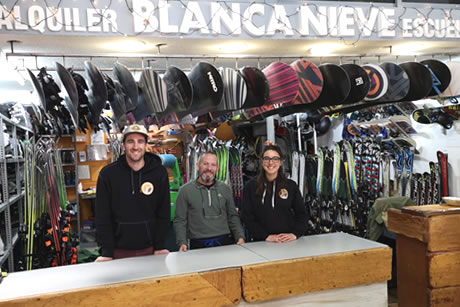 three-person team in their tent in front of the ski rental material